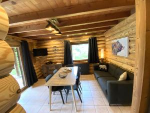 een woonkamer met een bank en een tafel bij L'OURS NOIR Chalet en rondins in La Bresse