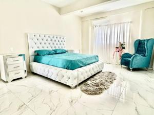 biała sypialnia z łóżkiem i niebieskim krzesłem w obiekcie Villa Familiar con Piscina cerca Av Ecológica w mieście La Ureña