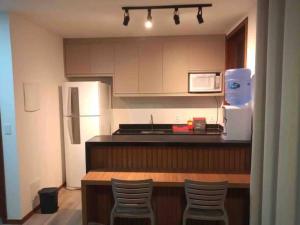 cocina con nevera, mesa y sillas en Apartamento 110 Viva Barra, en Maraú