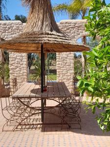 einen Tisch mit einem Strohschirm auf einer Terrasse in der Unterkunft Riad Mamy Wababi in Essaouira