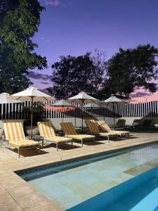 eine Gruppe von Stühlen und Sonnenschirmen neben einem Pool in der Unterkunft Hotel San German in Girardot