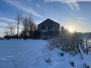 Eifelhaus UT Mutscheid في باد مونستريفل: منزل في حقل مغطى بالثلج مع غروب الشمس