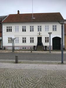 un grand bâtiment blanc avec un toit rouge dans l'établissement Apothekergaarden Stege B&B, à Stege
