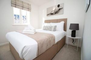 a white bedroom with a large bed and a window at Seymour Way Stunning 4 bed with FREE parking in Magor