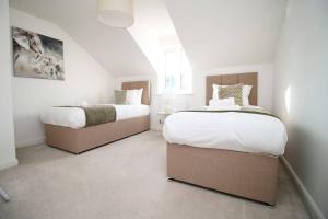 2 camas en un dormitorio con paredes blancas en Seymour Way Stunning 4 bed with FREE parking, en Magor