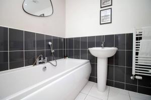 uma casa de banho com uma banheira branca, um lavatório e um espelho. em Seymour Way Stunning 4 bed with FREE parking em Magor