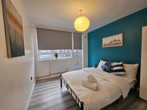 een slaapkamer met een bed en een blauwe muur bij London Mile End Rooms in Londen +50 foto's
