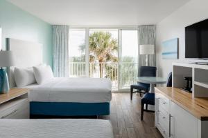 a hotel room with two beds and a desk at Tides Folly Beach in Folly Beach