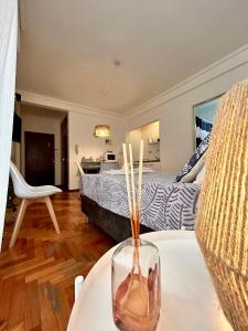 una sala de estar con una cama y un jarrón sobre una mesa en Rent Ibera Nuñez en Buenos Aires