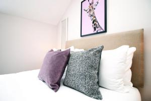 a bedroom with a bed with pillows and a giraffe picture at Stay with Free Parking at Archer Road Penarth in Cardiff