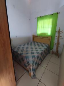 a small bedroom with a bed and a green window at Recanto dunas in Tutóia