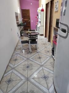 uma cozinha com uma mesa e cadeiras num piso de azulejo em Recanto dunas em Tutóia