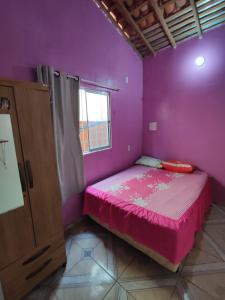 a purple bedroom with a bed and a window at Recanto dunas in Tutóia