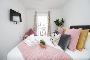 1 dormitorio con cama blanca y almohadas coloridas en Church Road Cardiff FREE parking en Cardiff