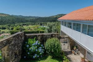 an external view of a house with a retaining wall and flowers at Casa Rural O Pozo in Borela