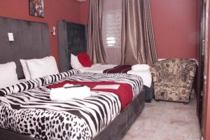 una habitación de hotel con 2 camas y una silla en Gold Crown International Hotel en Johannesburgo