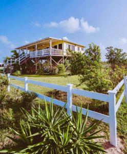 una casa su una collina con una recinzione bianca di Barbuda Cottages a Codrington Village