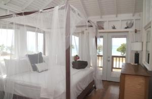 a bedroom with a canopy bed with a view of the ocean at Barbuda Cottages in Codrington Village
