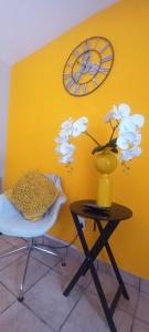 a yellow wall with a clock and a vase on a table at Platinum gem in the City of Rustenburg in Rustenburg