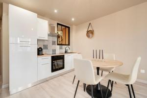 a kitchen with white cabinets and a wooden table and chairs at L'Elégance du centre - Nancy Gare Congrès - PARKING - T3 in Nancy