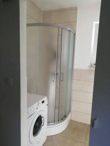 y baño con ducha y lavadora. en Charming flat, city center with free parking, en Varaždin