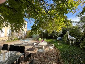 einen Garten mit Stühlen, Tischen und Giraffenstatuen in der Unterkunft La Demeure d'Othe in Sormery