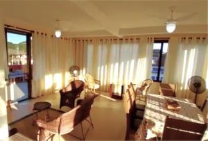 uma sala de estar com uma mesa, cadeiras e janelas em Apartamento Vista para o Mar em Maresias
