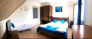 Un dormitorio con una cama azul y blanca y una mesa en Hanul Pescarilor, en Mila Douăzeci şi Trei
