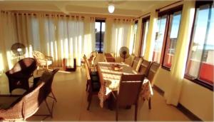 uma sala de jantar com mesa, cadeiras e janelas em Apartamento Vista para o Mar em Maresias