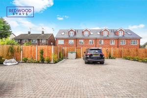 a car parked in a driveway in front of a house at BRAND NEW Spacious 4 Bedroom Houses For Contractors & Families with FREE Parking, Garden, Fast Wifi and Netflix By REDWOOD STAYS in Farnborough