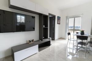 uma sala de estar com uma televisão de ecrã plano na parede em Luxurious Beach Apartment em Birzebbuga