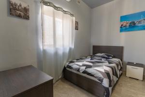 um quarto com uma cama e uma janela em Luxurious Beach Apartment em Birzebbuga