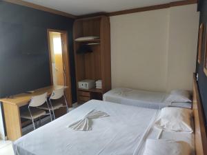 a hotel room with two beds and a desk and a desk at Golden Dolphin Grand Hotel in Caldas Novas