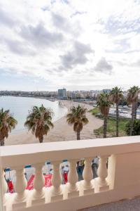 uma vista a partir da varanda de uma praia com palmeiras em Luxurious Beach Apartment em Birzebbuga