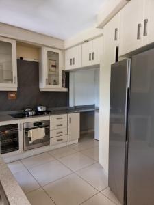 a kitchen with white cabinets and a stainless steel refrigerator at 56 Archer Crescent Mainhouse in Durban