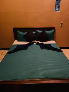 a bed with green sheets and pillows on it at Winston Dutch Canal Villa Guest House in Negombo