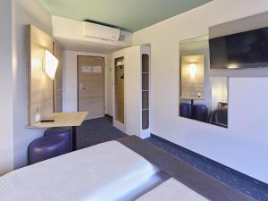 a room with a bed and a desk and a tv at B&B Hotel Dortmund-City in Dortmund