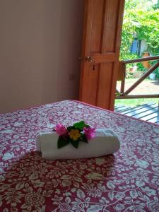 Una cama con una almohada con una flor. en Hostal Makohe Rapa Nui, en Hanga Roa