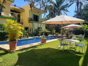 a patio with a table and an umbrella next to a pool at Casa Jardín del Tuito in El Tuito