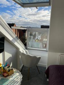 1 dormitorio con una silla blanca y una ventana en Redwing Rise en Royston