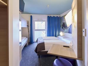 ein Hotelzimmer mit 2 Betten und einem Tisch in der Unterkunft B&B Hotel Dortmund-City in Dortmund