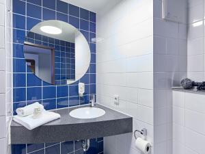 W wyłożonej niebieskimi kafelkami łazience znajduje się umywalka i lustro. w obiekcie B&B Hotel Dortmund-City w Dortmundzie