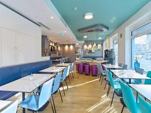 a dining room with tables and blue chairs at B&B Hotel Dortmund-City in Dortmund