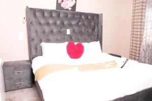 Una cama con una almohada de corazón roja. en Gold Crown International Hotel en Johannesburgo