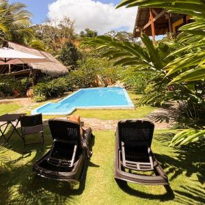 two chairs sitting in the grass near a swimming pool at Canto del Río Lodge in Tarapoto