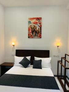 a bedroom with a white bed with a painting on the wall at Devon Surf . Inn - Hiriketiya in Dickwella