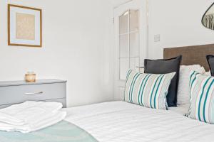 a white bed with striped pillows in a bedroom at Bramcote Lane Spacious 5 BR House in Nottingham