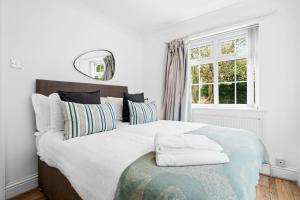 een slaapkamer met een groot bed met kussens en een raam bij Bramcote Lane Spacious 5 BR House in Nottingham
