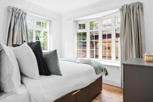 sypialnia z łóżkiem z poduszkami i oknami w obiekcie Bramcote Lane Spacious 5 BR House w Nottingham