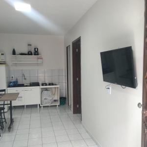 a kitchen with a flat screen tv on a wall at Apto 03 - 1 quarto com 2 camas solteiro e garagem, possui ventilador de teto in Cascavel +5 photos